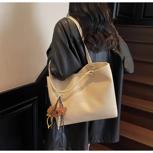Close-up of cream faux leather tote bag with lychee texture and cute bear charm