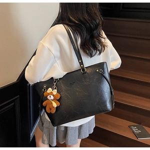 Détail du grand sac cabas en similicuir noir avec un pendentif ours en peluche