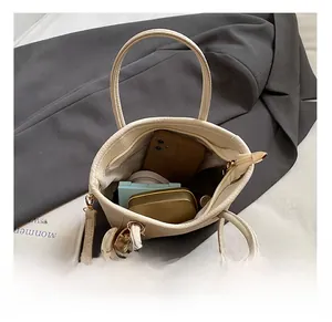 Detailansicht des geräumigen Innenraums der cremeweißen Leder-Beuteltasche mit Inhalt