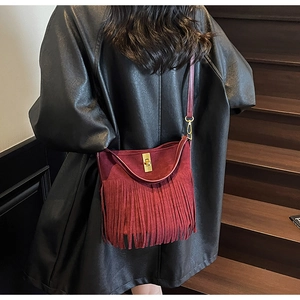 Detail of burgundy fringe crossbody bag with gold twist lock and matte leather finish