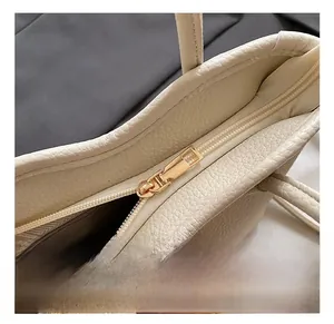Nahaufnahme des goldenen Reißverschlusses und der Lederstruktur auf der weißen Tasche