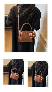 Detail view of brown lychee grain leather tote with golden logo and plush monster charm