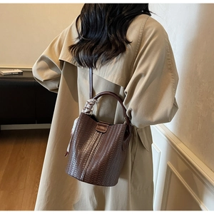Détail du sac seau tissé avec poignée en cuir marron et foulard en soie à imprimé vintage