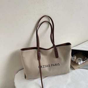 Détail d'un sac cabas en toile beige avec poignées en cuir marron et logo PARIS