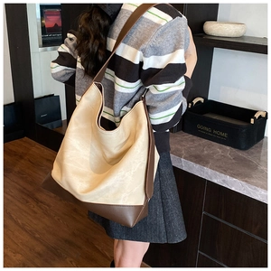 Model wearing large capacity patchwork faux leather tote bag in beige and dark brown color
