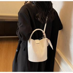 Vue détaillée de la texture tressée blanche d'un sac seau avec un foulard en soie décoratif