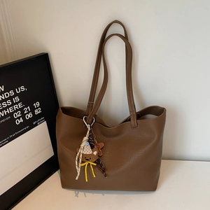 Detail of dark brown lychee grain tote bag featuring a cute plush bear charm