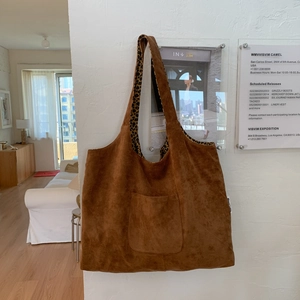 Close-up of brown suede tote bag featuring contrast leopard print lining and outer pocket