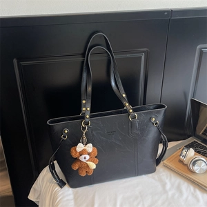 Détail d'un cabas noir en PU avec rivets dorés et charmant pendentif d'ours en peluche brun