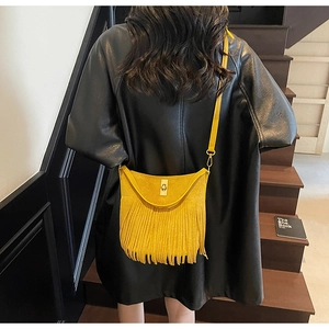 Detail of vibrant yellow fringe crossbody bag with gold twist lock and suede texture