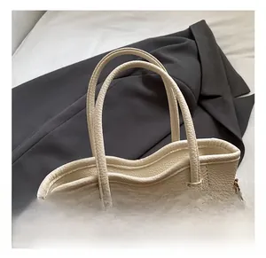 Detail der Tragetasche aus Leder mit Lychee-Struktur und goldenem Metallanhänger
