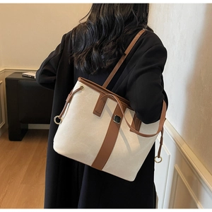 Vue arrière d'un mannequin portant un grand sac cabas en toile beige et cuir marron