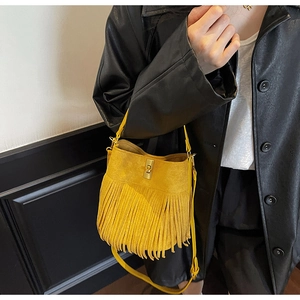 Close-up of vibrant yellow bohemian bucket bag featuring soft suede fringe and gold twist lock