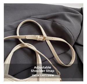 Detail eines verstellbaren Lederriemens mit goldener Schnalle an cremefarbener Tasche