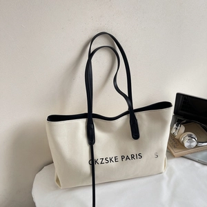Gros plan d'un sac cabas en toile minimaliste avec anses en cuir noir et ordinateur portable
