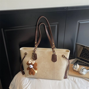 Détail d'un grand sac cabas en similicuir crème avec porte-clé ours et cordon latéral