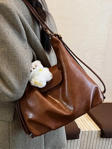 Grand sac cabas marron en cuir avec charme pelucheux sur blazer gris élégant