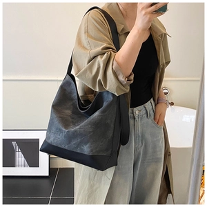 Detail of a large grey PU leather tote bag with a black reinforced base for daily use