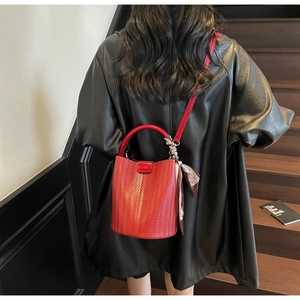 Détail d'un sac seau tressé rouge avec foulard en soie et bandoulière sur modèle