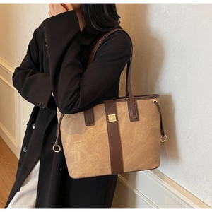 Détail d'un grand sac fourre-tout marron avec bandoulière en cuir et logo doré