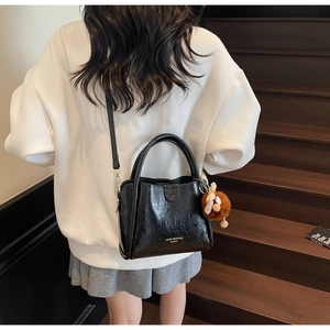 Detailed back view of a black lychee texture tote bag worn by a model on stairs