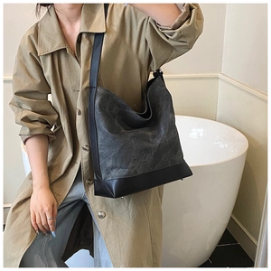 Detail of grey and black patchwork Hobo bag worn by a model in a minimalist setting