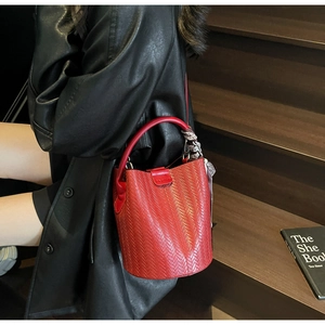 Détail d'un sac seau tissé rouge avec foulard en soie sur un escalier élégant
