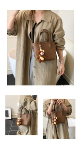 Detailansicht der braunen Leder-Eimertasche mit Bärenanhänger und abnehmbarem Schultergurt