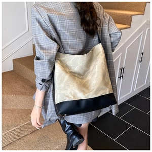 Detail of a large capacity two-tone tote bag with beige textured fabric and black leather base