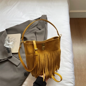 Detail of bohemian yellow suede bag with long tassels and vintage golden metal buckle