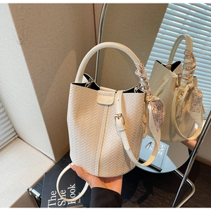 Détail d'un sac seau blanc tressé avec poignée en foulard de soie et logo FASHION