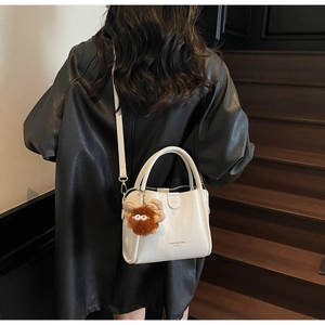 Close-up of white lychee pattern handbag with cute brown fur ball charm detail