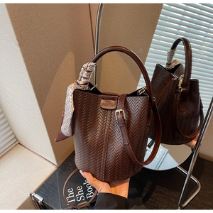 Détail du sac seau marron foncé avec foulard en soie et texture tressée élégante en forme de V