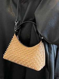 Brown suede crescent bag with pearl rivets and silver hardware on leather background