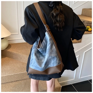 Detail of stone-washed blue tote bag with dark brown leather straps and base