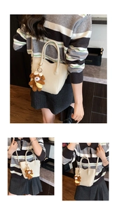Detail der beigen Handtasche mit strukturiertem Leder und süßem braunem Plüschbär-Anhänger