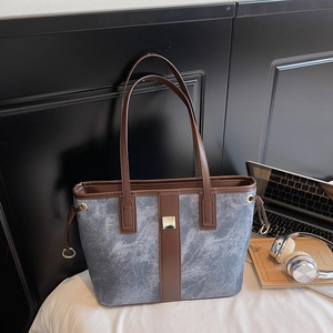 Détail du cabas en toile marbrée bleue avec garniture en cuir brun et boucle dorée