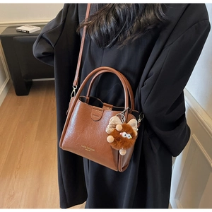 Detail of a brown lychee pattern tote bag with a plush charm and adjustable strap