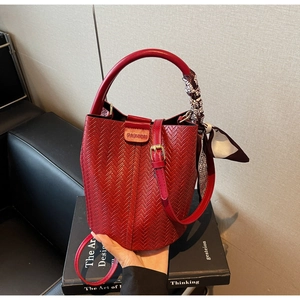 Détail du sac seau rouge tissé avec logo tendance et écharpe en soie décorative sur l'anse