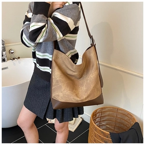 Side view of large retro khaki brown PU leather tote bag worn by a model in a modern room