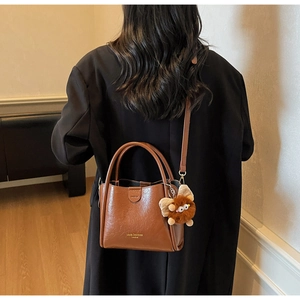 Brown lychee texture leather handbag with monster charm shown in a fashion lifestyle setting