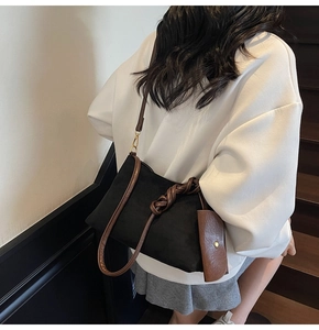 Dettaglio borsa tote in pelle scamosciata nera con manici intrecciati e mini pochette