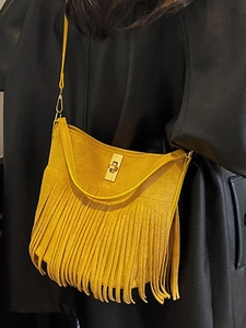 Bohemian mustard yellow fringe crossbody bag with gold buckle on black leather jacket