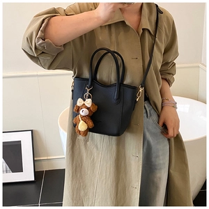 Detail der schwarzen Tote-Bag aus Leder mit einem süßen braunen Teddybär-Anhänger