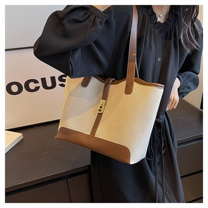 Detail of canvas tote bag with brown leather trim and golden metal lock for women