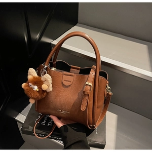Detailed macro view of the brown lychee grain texture and gold branding on the leather handbag