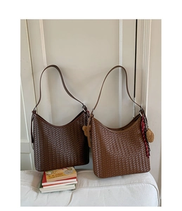Détail de sacs seaux tressés à la main en marron foncé et caramel avec pompons doux