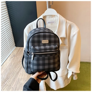 Detail view of the black and gray checkered backpack with metal brand plate and zipper