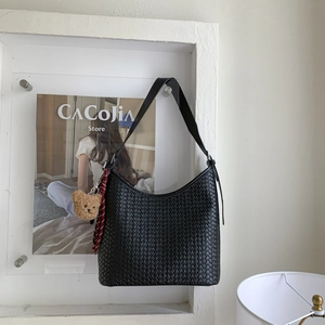 Détail d'un sac hobo noir tressé avec un charm d'ours et une texture artisanale unique