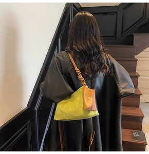 Dettaglio borsa a secchiello intrecciata verde con tracolla a nodo e mini borsa su pelle